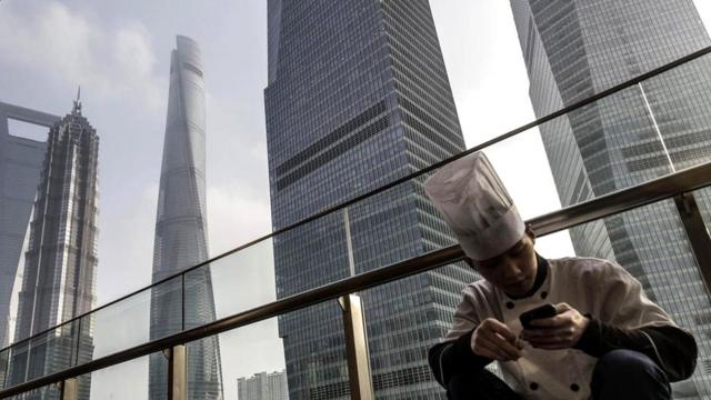 Китаец со смартфоном на фоне небоскребов