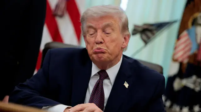 Дональд Трамп с гримасой на лице за столом в Овальном кабинете