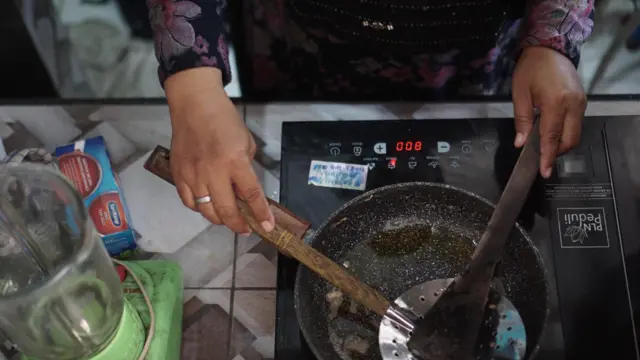 Warga memasak menggunakan kompor listrik induksi di Kampung Mojo, Semanggi, Solo, Jawa Tengah, Selasa (27/09)