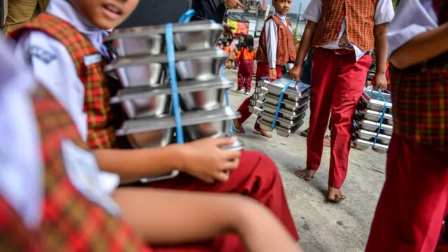 Siswa membawa Makanan Bergizi Gratis (MBG) untuk dibagikan, Selasa (31/03).