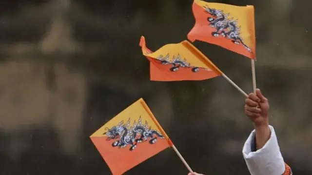 भुटानको झण्डा हातमा बोकेर फहराइँदै