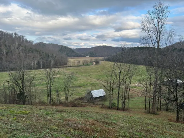 Un granero en unas colinas con árboles.