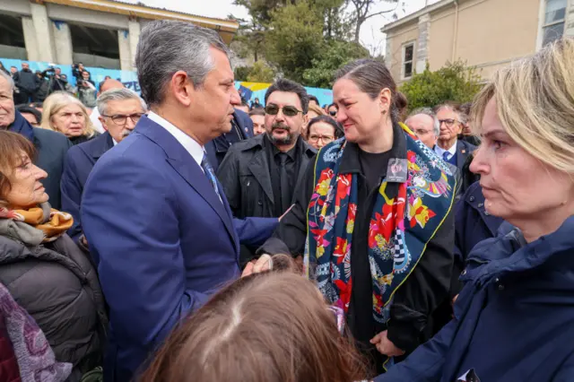 Özgür Özel önde, İlber Ortaylı'nın kızı Tuna Ortaylı Kazıcı ile el sıkışıyor. Arkada pek çok katılımcı var. 