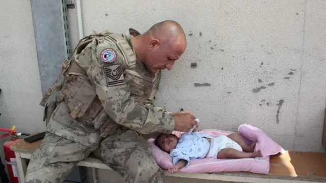 কাবুল বিমানবন্দরে এক শিশুর সেবা করছে তুরস্কের এক সৈন্য। বহু পরিবার এখন বিমানবন্দরে অপেক্ষা করছে।