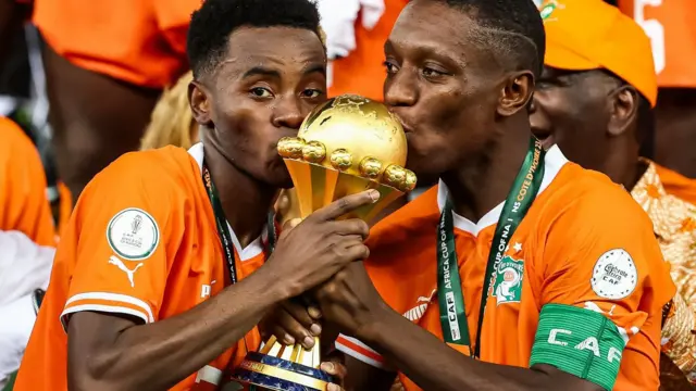 Les joueurs ivoirien Max Alain Gradel (Droite) et Simon Adingra embrassent le trophée de la CAN 2023.