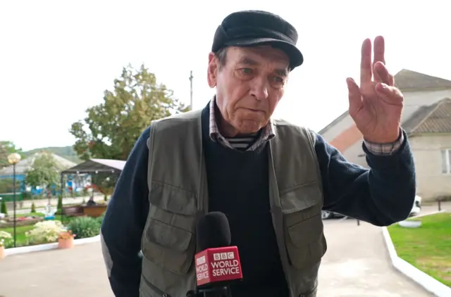 Володимир Володимирович - чоловік у кепці і жилетці підняв руку вгору