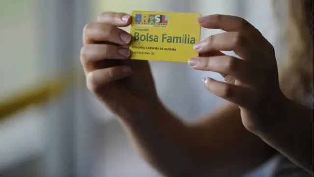 Mulher segura cartão do Bolsa Família