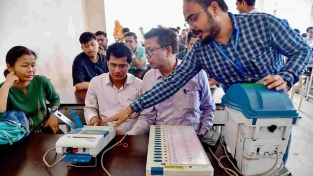 चुनाव अधिकारी मतदान चरण से पहले इलेक्ट्रॉनिक वोटिंग मशीन (ईवीएम) तैयार करते हुए