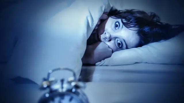 Mujer en la cama con ojos abiertos.