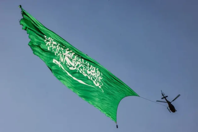 یک هلیکوپتر که پرچم عربستان سعودی را در آسمان به اهتزاز درآورده