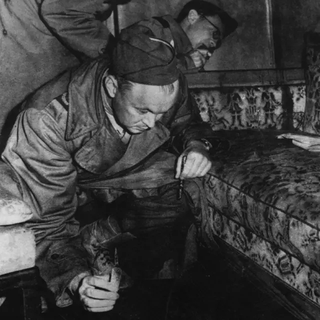 1945 मध्ये मित्र राष्ट्रांच्या युद्ध पत्रकारांनी हिटलरच्या बंकरमधील सोफ्याचं निरीक्षण केलं - असं म्हटलं जातं की खुर्चीच्या हातावर रक्ताचे डाग आहेत
