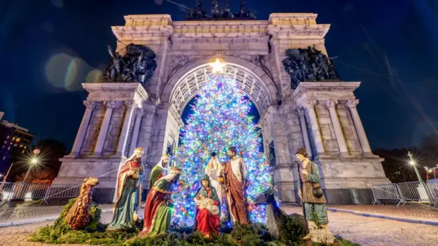 Шопка в Нью-Йорку - кольорові фігурки Ісуса, його батьків, царів і пастушків на фоні великих архітектурних воріт у вечірній час