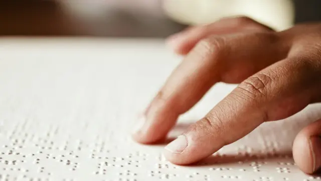 Braille alfabesiyle kitap okuyan bir kişi