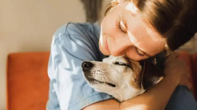 ውሻዋን ያቀፈች ሴት