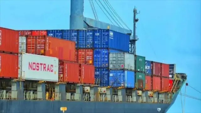 تصویر یک کشتی را در لنگرگاه بندر چابهار نشان می‌دهد که پر از کانتینرهای رنگارنگ است.