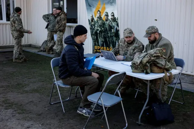 Militares conversam com um jovem em ponto de recrutamento