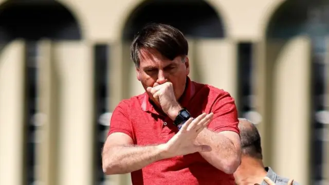 Bolsonaro cobre a boca com a mao