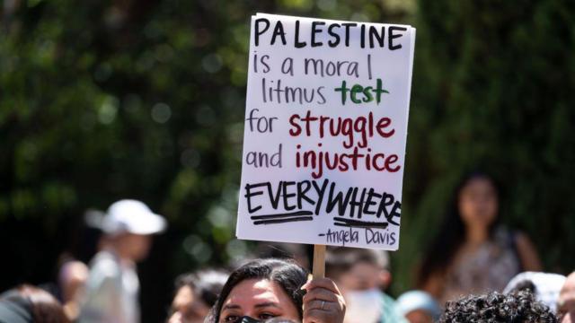 Uma manifestante pró-Palestina segura um cartaz no campus da UCLA em Los Angeles em 29 de abril de 2024