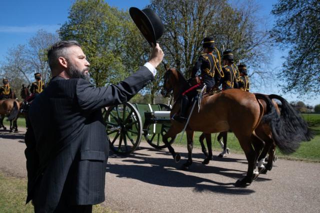 A person salutes the King's Troop Royal Horse Artillery as they make their way down the Long Walk towards Windsor Castle, as the funeral of the Duke of Edinburgh takes place in St George's Chapel, at Windsor Castle, Berkshire