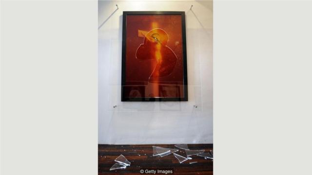 塞拉诺1987年的作品中，受难的耶稣浸在装有摄影师尿液的烧杯里，2011年在法国展览时遭到蓄意破坏。