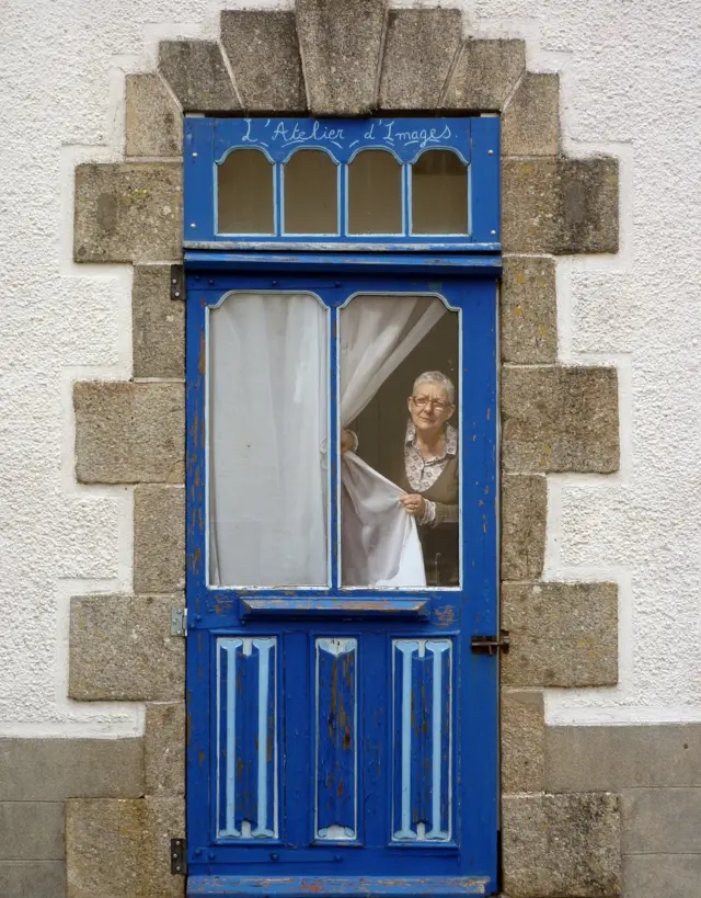Una mujer mirando a través de una ventana.