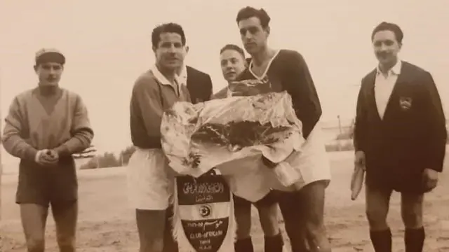 محمد مزاحي (خلف الرجال الذين يحملون الزهور) خلال مباراة أدارها عام 1956