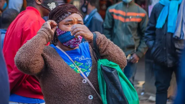 Women dey try adjust mask