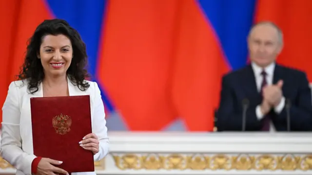 RT總編輯瑪格麗塔·西蒙尼揚出席一場簽署儀式，背景中可見俄羅斯總統弗拉基米爾·普京