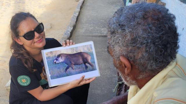 Pesquisadora conversa com morador de comunidade local durante expedição