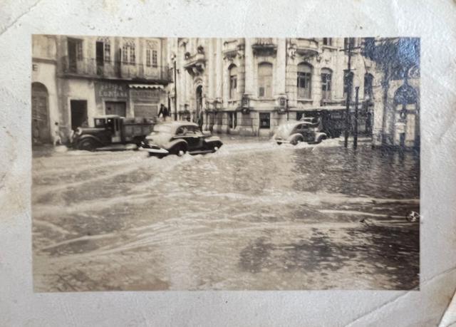 Carros passando por rua alagada