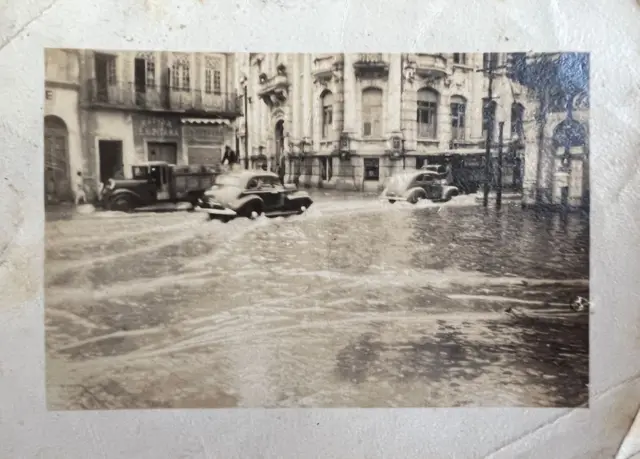 Carros passando por rua alagada