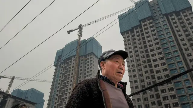 一个老人走在正在修建中的楼盘下