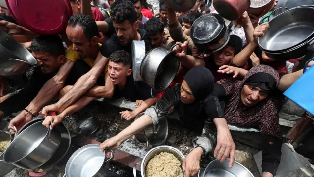 People waiting to receive food cooked by a charity in Jabalia, Gaza