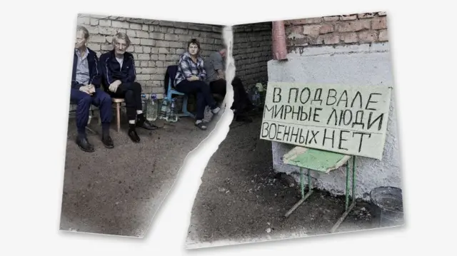 Группа людей сидит у входа в подвал у кирпичной стены, рядом плакат с надписью «В подвале мирные люди, военных нет».