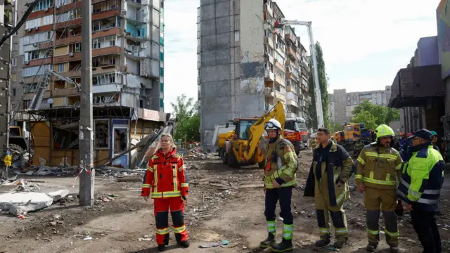 Неколико људи у спасилачким оделима испред рушевина погођене зграде