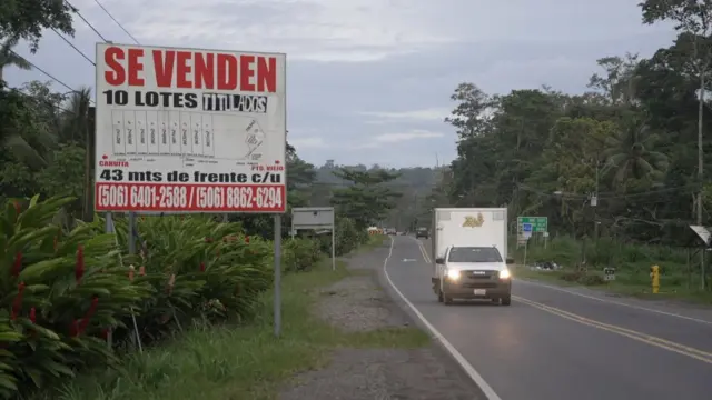 Una anuncio publicitario al costado de una carretera ofrece venta de lotes de tierra con título de propiedad.
