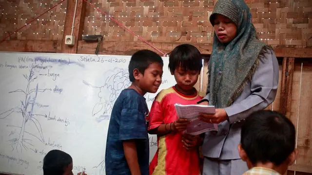 Para siswa belajar bersama guru mereka di sebuah sekolah darurat di lokasi pembuangan sampah Bantar Gebang—salah satu tempat pembuangan sampah di Jakarta—pada tanggal 26 Januari 2010 di Jakarta.