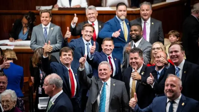 法案可決を喜ぶ共和党議員たちが議場内でまとまって立ち、カメラに向かって笑顔で親指を立てている