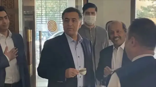 فیض حمید او ورسره په کابل کې د هغه مهال پآکستان سفیر په کابل سیرینا هوټل کې د چایو پیالې په لاس کامرې ته خاندي.