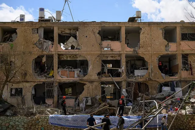 Trabajadores despejan edificios destruidos en Dimona, Israel, este domingo tras el impacto de un misil balístico iraní que dejó más de 50 heridos.