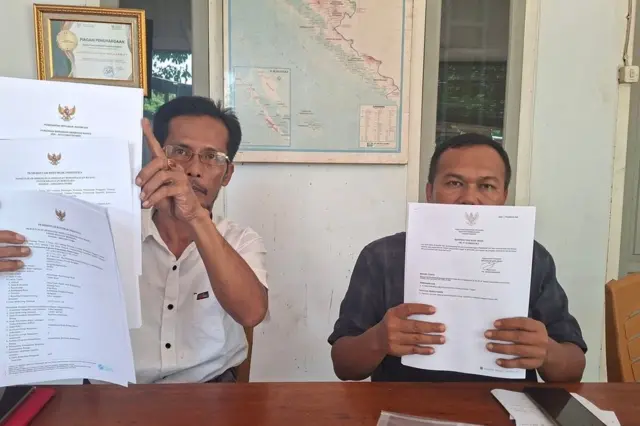 Dua orang sedang menunjukkan berkas dokumen.