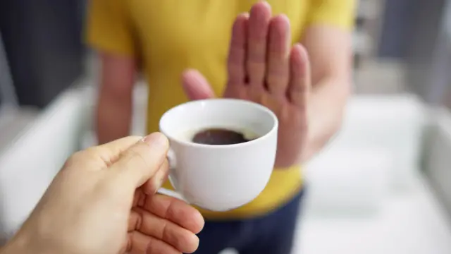 Pessoa oferecendo café enquanto a outra estende a mãojoao rock betsulsinaljoao rock betsulnegação