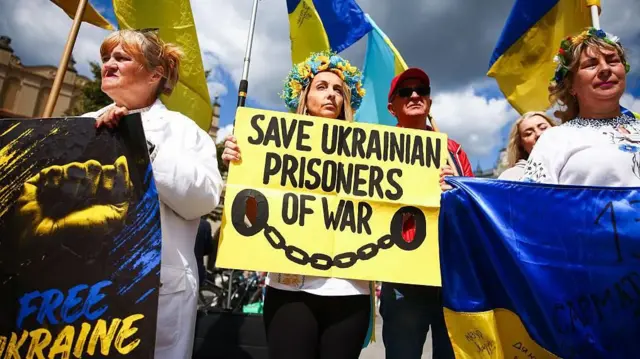 Manifestantes sostienen pancartas que exigen la liberación de los prisioneros de guerra ucranianos. Lucen los colores nacionales de Ucrania y un gran cartel que dice 
