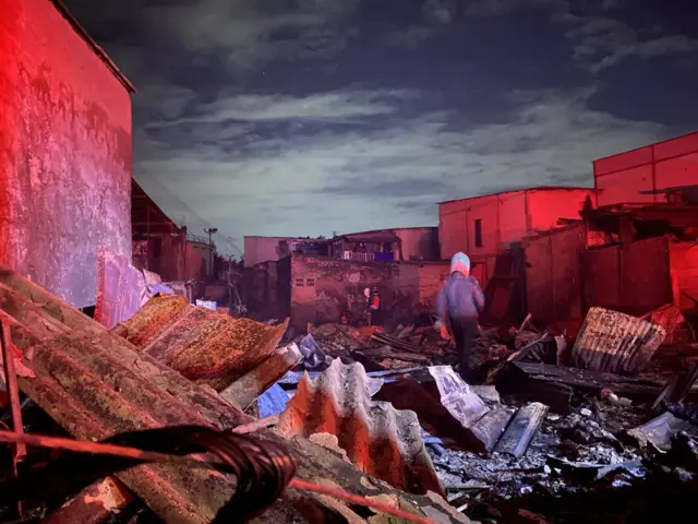 Petugas pemadam kebakaran berada di reruntuhan bangunan warga yang ikut terbakar akibat kebakaran yang melanda Depo Pertamina Plumpang, Jakarta, Sabtu (04/03).