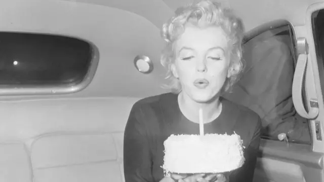 Marilyn Monroe sopla la vela de una tarta el 1 de junio de 1956