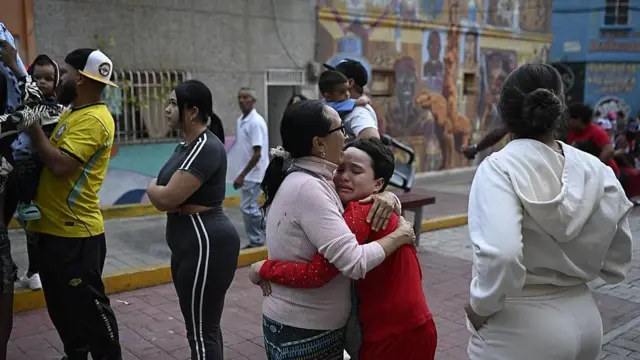 Una mujer consuela a un niño en la calle en Caracas. Tambén se ve a otras personas que permanecen en la calle por temor a réplicas