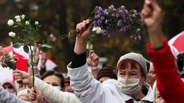 Mulheres, jovens e idosas, com máscaras contra o coronavírus e levantando floreshandicap (0) 1xbet significationprotesto na rua