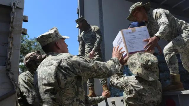 Unos soldados descargan cajas de un camión