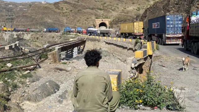 Torkham sınır kapısında, kamyonunun yanında oturmuş bekleyen bir şoför
