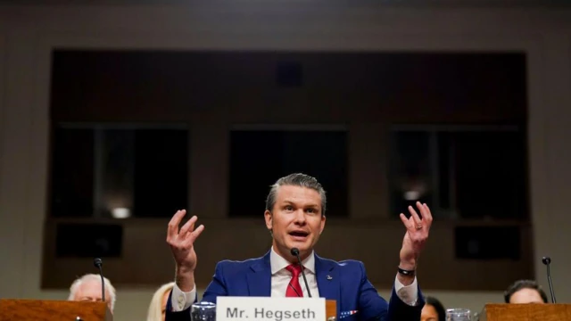 هگست پشت تریبون دست‌هایش را بالا برده و در حال صحبت